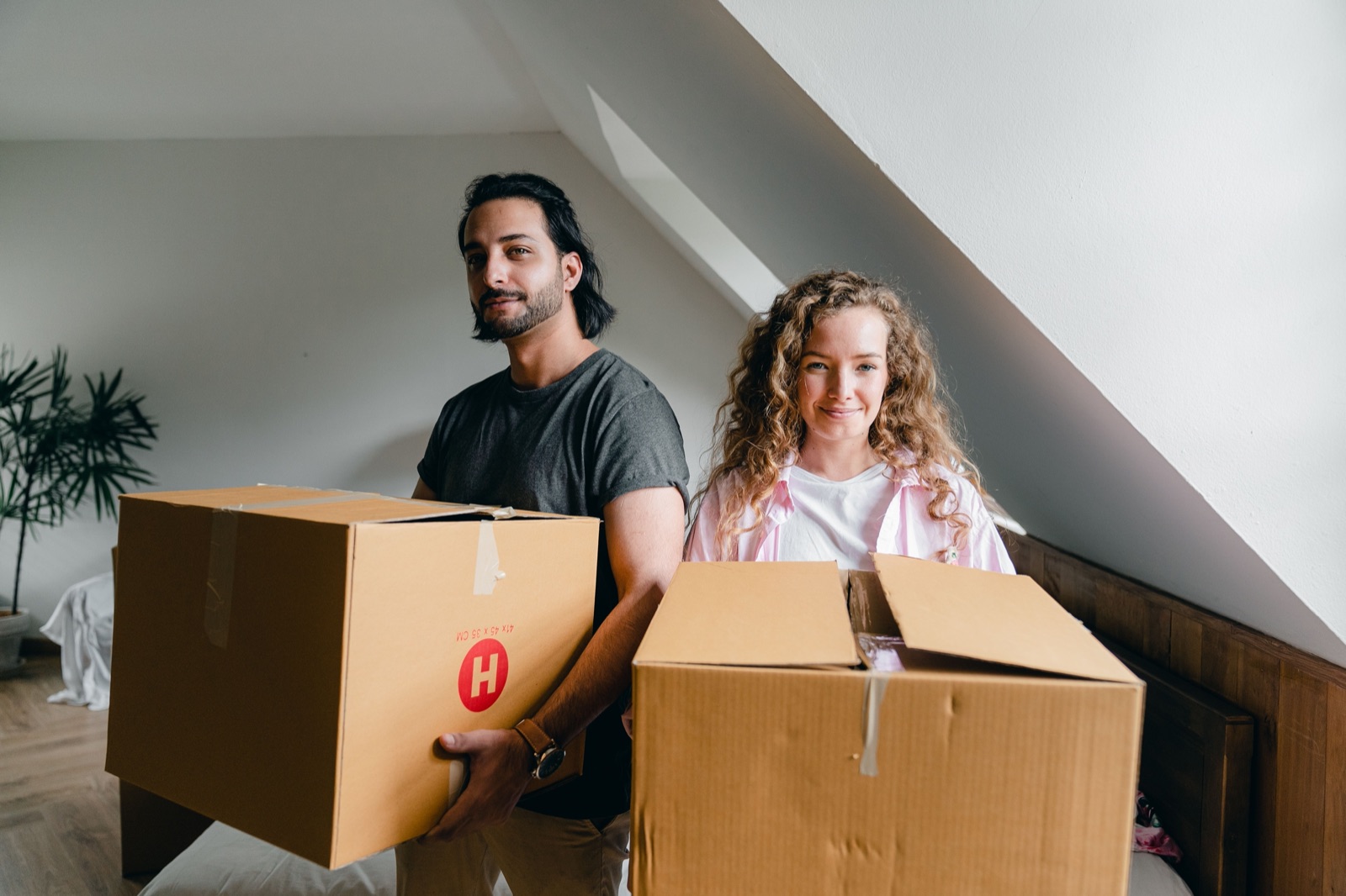 Couple carrying moving boxes into their new place